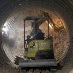 Miniescavadeira, chapas de aço e concreto projetado compõem a base dos túneis do Drenar DF