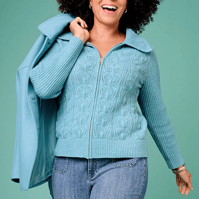 Mulher negra usa suéter plus size de malha com jeans; jaqueta tem zíper e gola larga