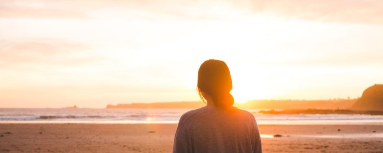 Mulher fica na praia olhando para o sol; Ela deseja ter comprado um kit de protetor solar para tentar em 2025