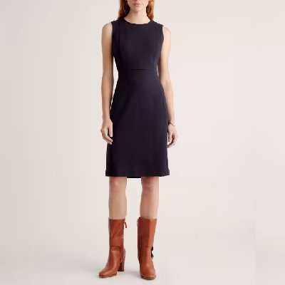 Uma mulher vestindo um vestido preto sem mangas e botas marrons