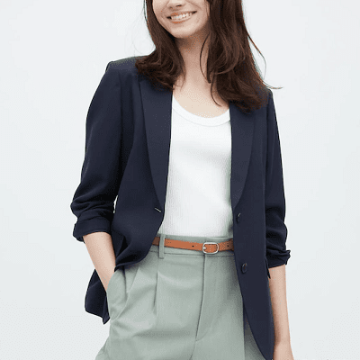 Mulher usa blazer azul, tanque branco e calças cáqui verdes claras