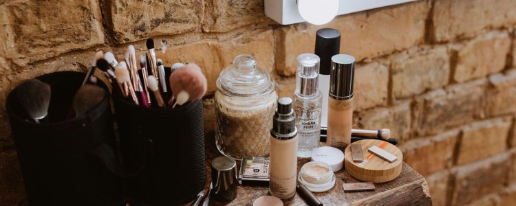 loções e soros sentam -se em um balcão de madeira na frente de uma luz; eles podem ser produtos de beleza comprados repetidamente