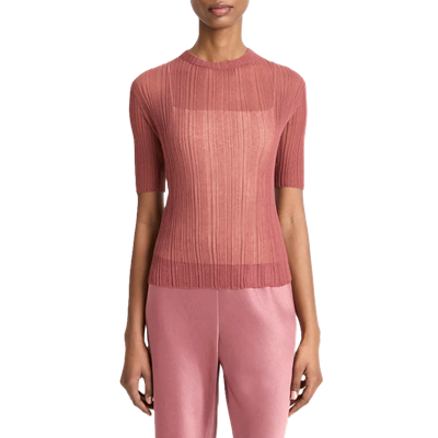 Mulher usa suéter de malha de ponto aberto rosa macio com uma camisola branca embaixo