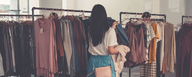 Mulher olha para a prateleira de roupas; Ela está tentando subir de nível seu estilo pessoal