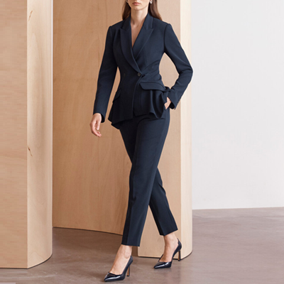 mulher usa terno azul marinho com calças levemente curtas e detalhes de babados