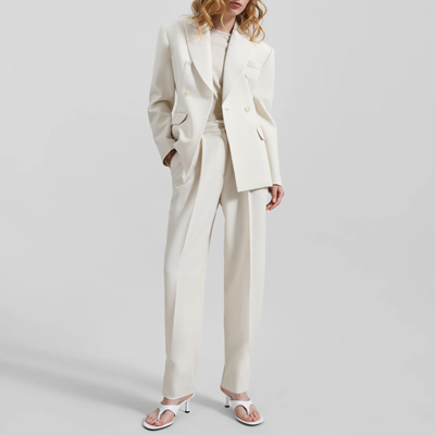 mulher usa terno trespassado creme/marfim com calças plissadas e afuniladas