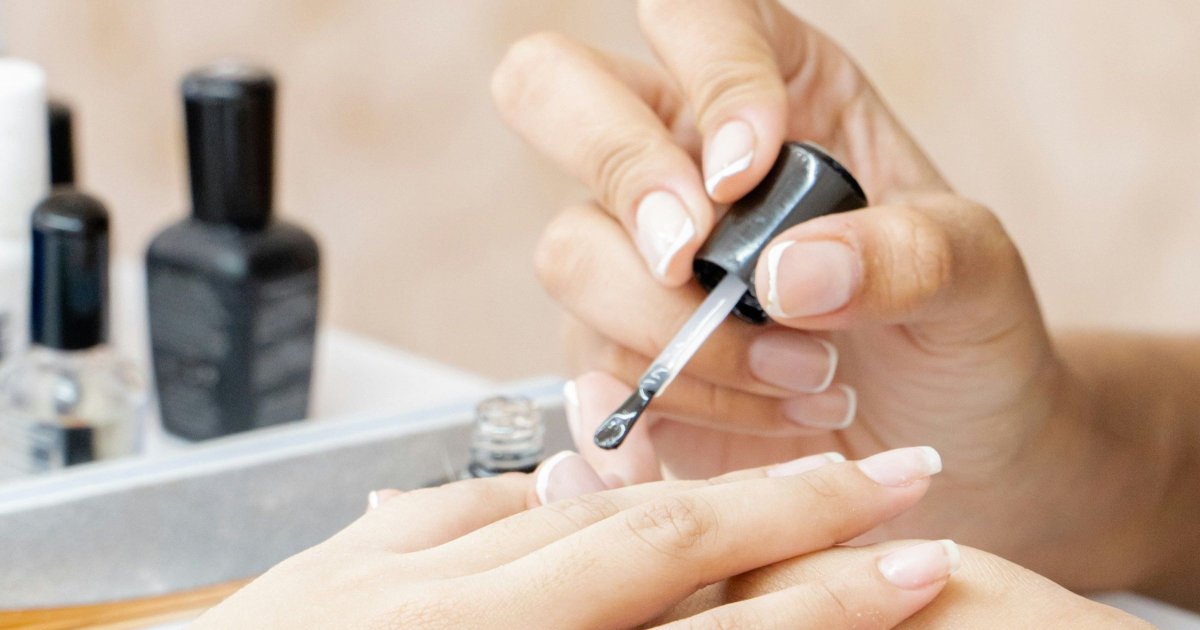 mulher faz manicure (close das mãos)