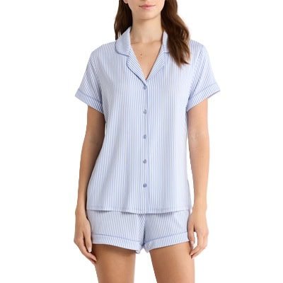 Uma mulher (rosto e pernas cortados) vestindo um conjunto de pijama com shorts listrados em branco e azul