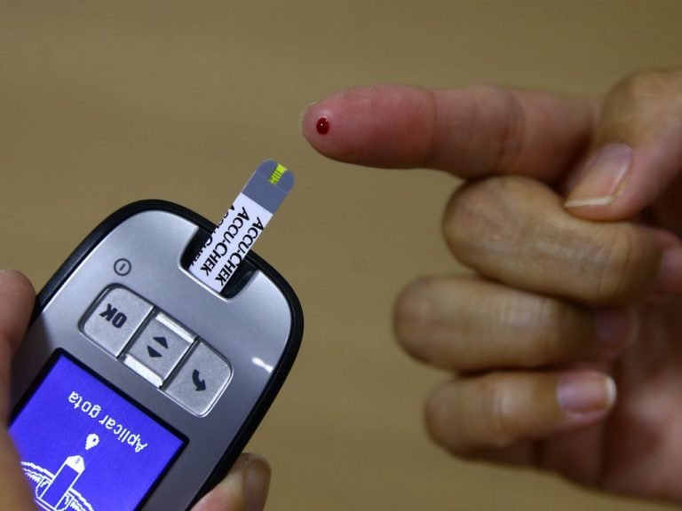 Aparelho medidor de glicose para teste rápido de açúcar no sangue. Pessoa com o dedo furado fazendo o teste.